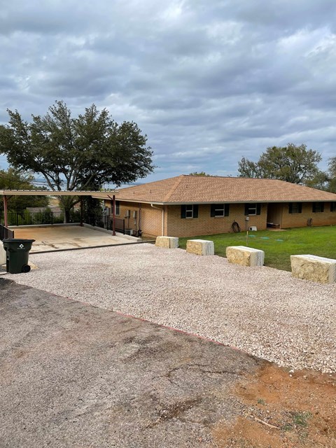 A house with a brown roof and a driveway with gravel.
