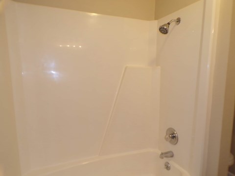 A white bathtub with a shower head and faucet.