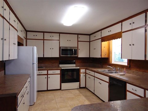 A kitchen with white cabinets and brown countertops.