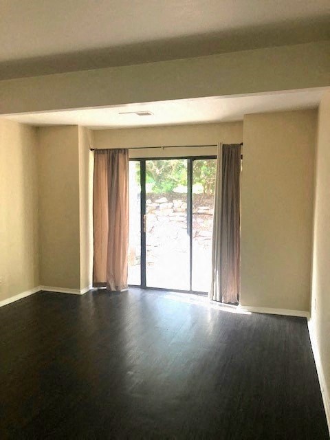 an empty living room with wood floors and sliding glass doors