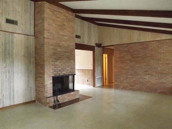 an empty living room with a brick fireplace