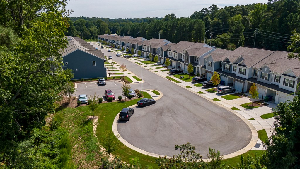 an aerial view of a neighborhood of houses with cars parked on a street