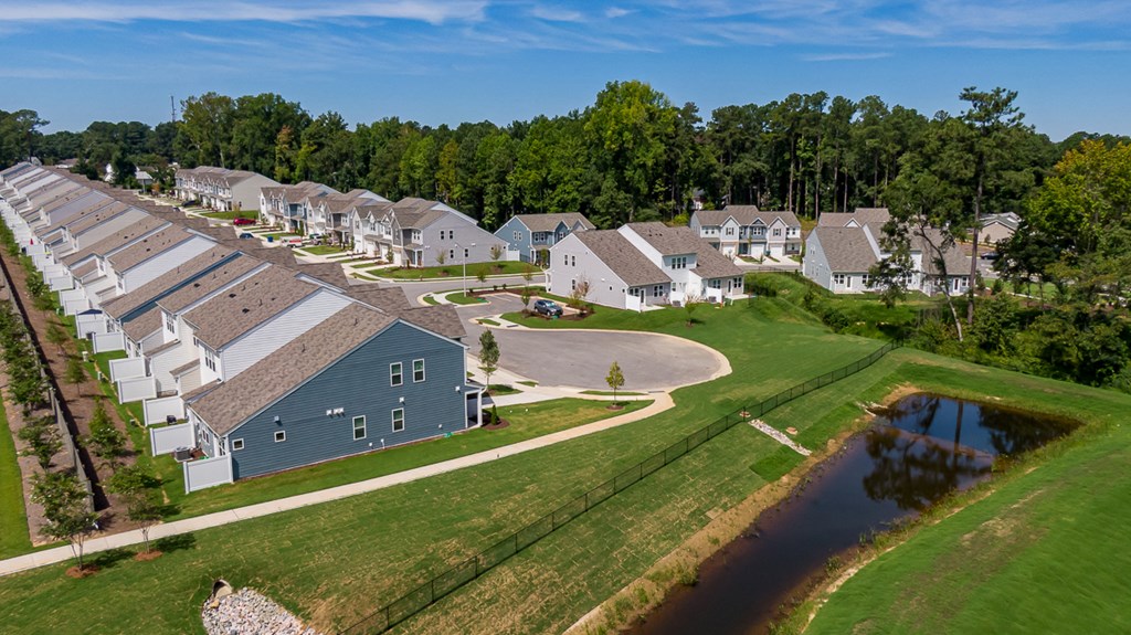 an aerial view of a neighborhood of houses next to a pond
