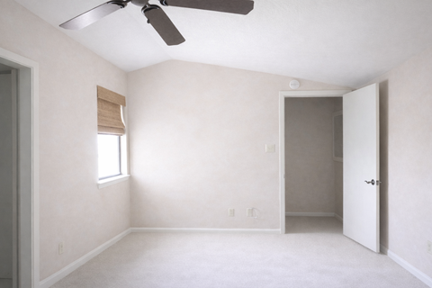 A room with a ceiling fan and a window with blinds.