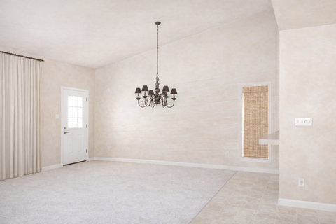 A room with a chandelier and a window with curtains.