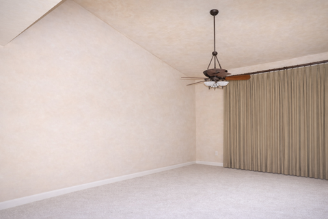 A room with a ceiling fan and a window with curtains.