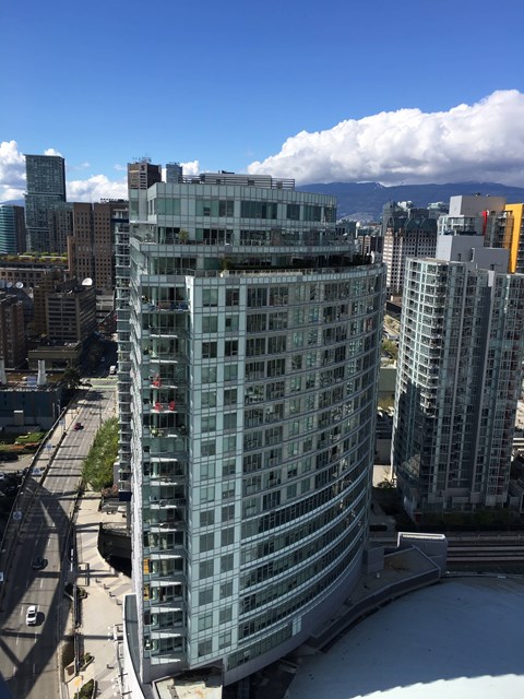 A tall glass building stands in the middle of a city.