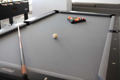 A pool table with a white ball and a cue stick.