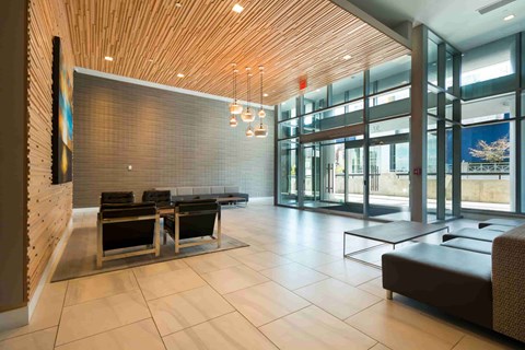 A modern waiting room with a wooden ceiling and glass doors.
