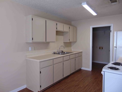 an empty kitchen with white cabinets and a sink