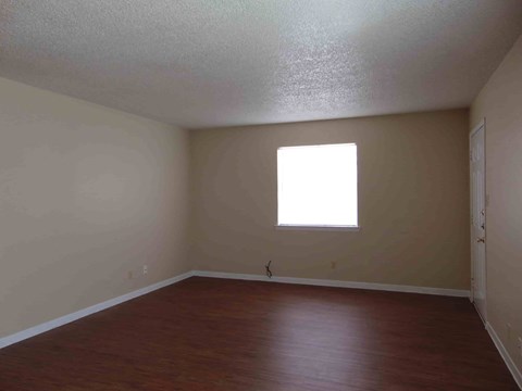 an empty room with wooden floors and a window