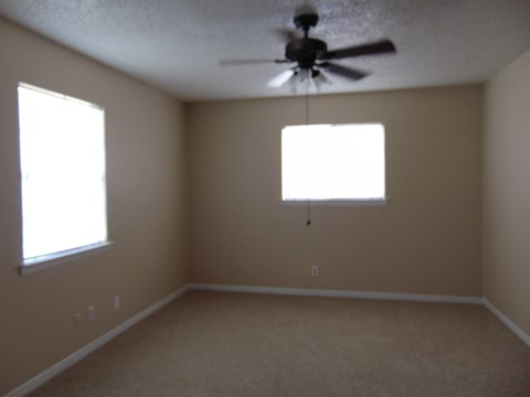 a living room with a ceiling fan and two windows