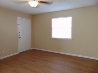 an empty living room with a ceiling fan and a window