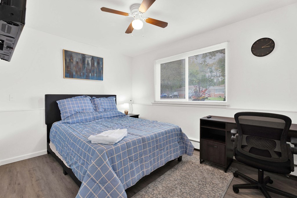 A bedroom with a bed, desk, and chair.