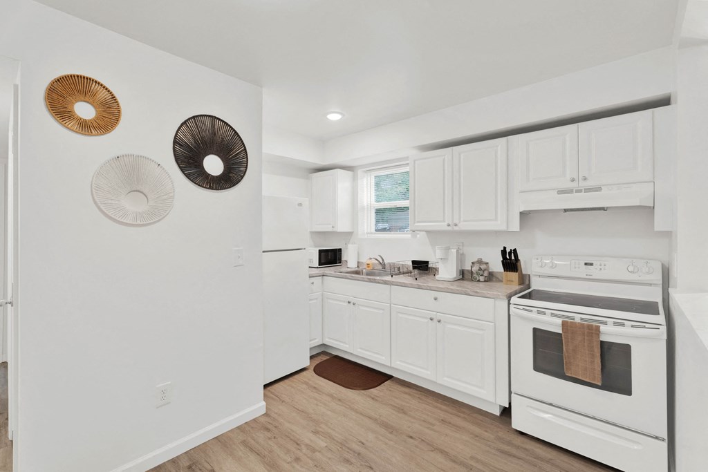A white kitchen with a white oven and white cabinets.