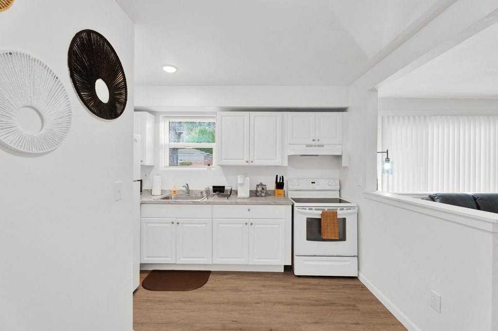 A white kitchen with a fan on the wall.