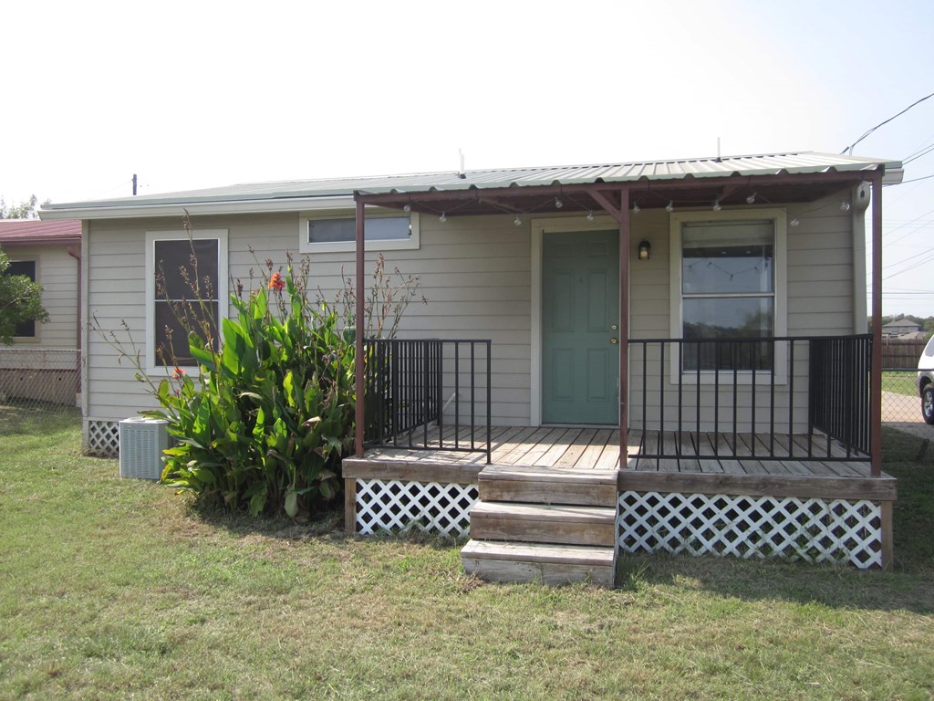 the front of a house with a porch and a green door