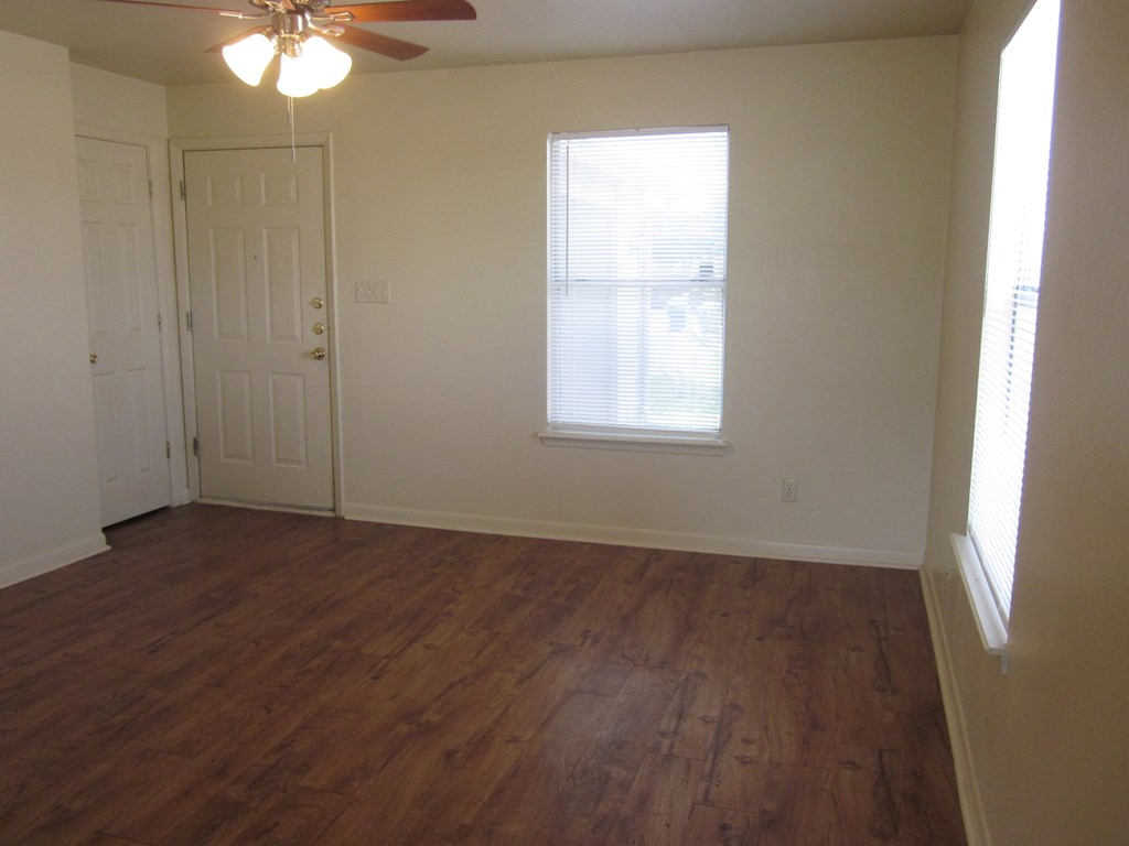 an empty living room with wood floors and a window