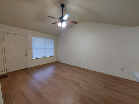 A room with a ceiling fan and wooden flooring.