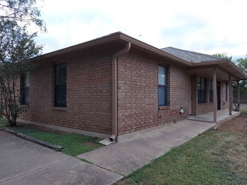 A brick house with a porch and a covered entry way.