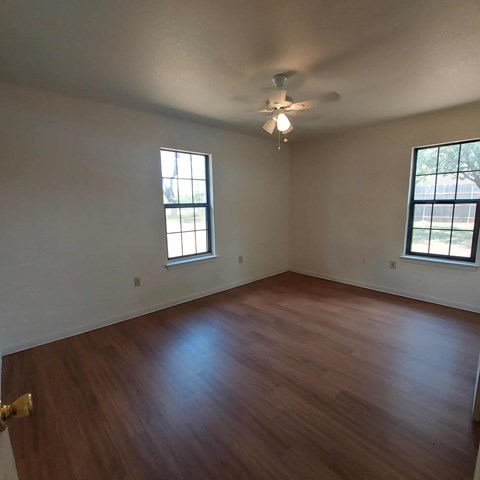 A room with wooden floors and two windows.