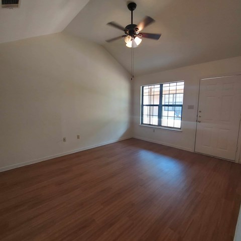 A room with a ceiling fan and wooden floors.