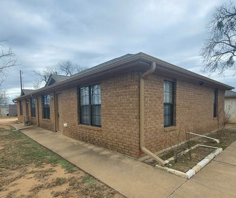 A brick house with a brown roof and a white door.