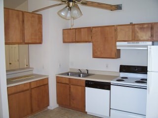 A kitchen with brown cabinets and a white fridge.