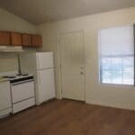A kitchen with white appliances and wooden floors.
