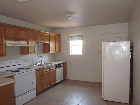 an empty kitchen with white appliances and wooden cabinets
