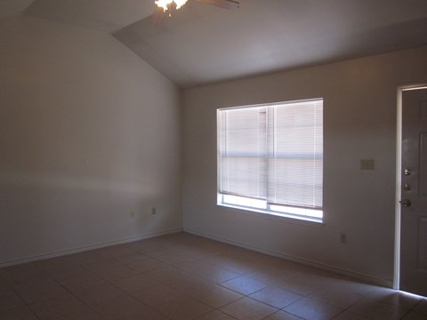 an empty living room with a window and a tiled floor