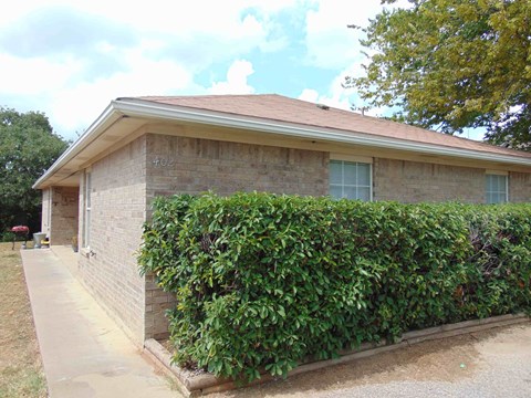 a brick house with a hedge in front of it