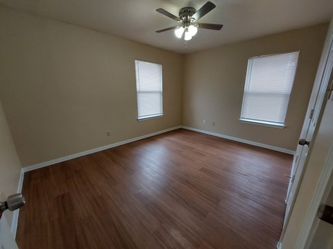 A room with a ceiling fan and wooden flooring.