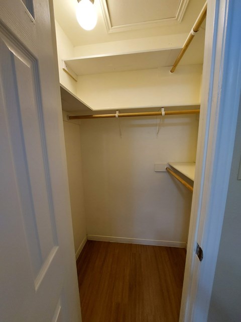 A small, empty room with a wooden floor and white walls.