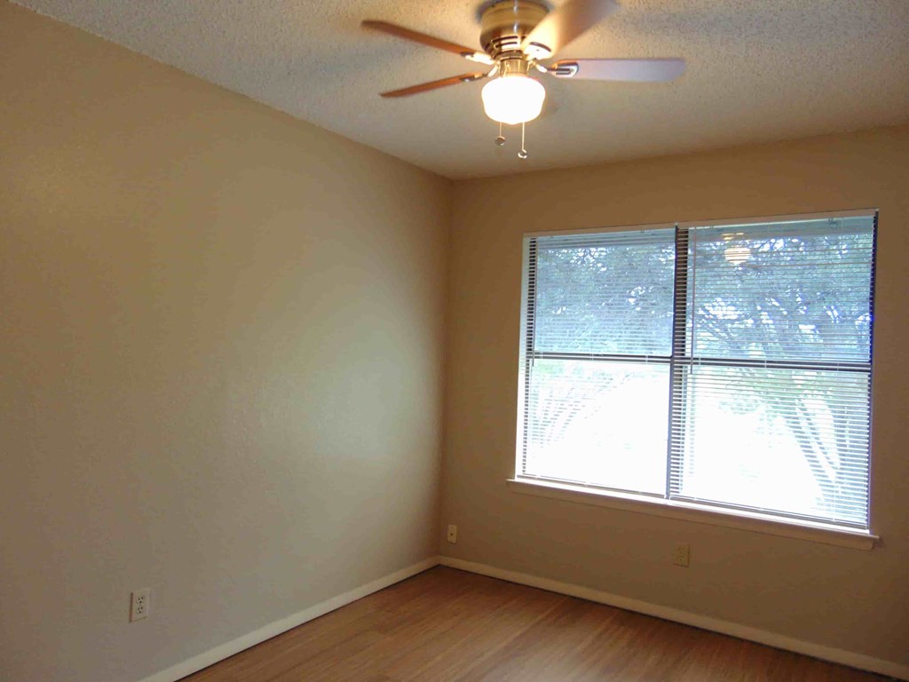 an empty room with a ceiling fan and a window