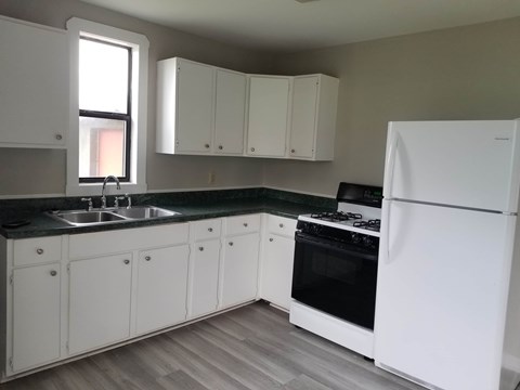 A kitchen with white appliances and cabinets.