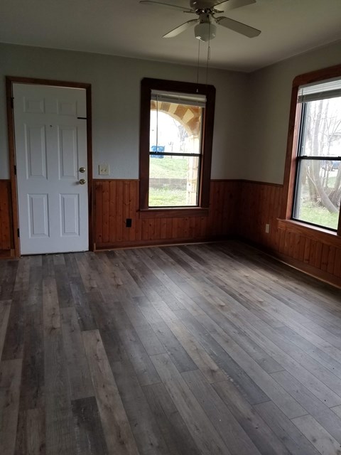 A room with a white door and a window with a view of trees.