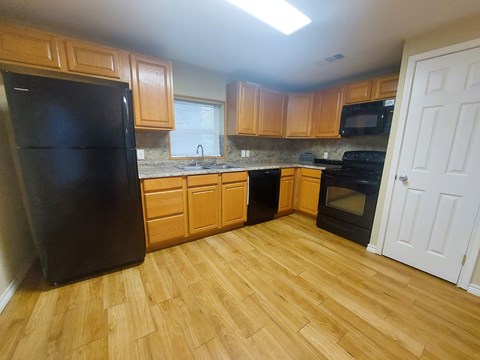 A kitchen with wooden cabinets and black appliances.