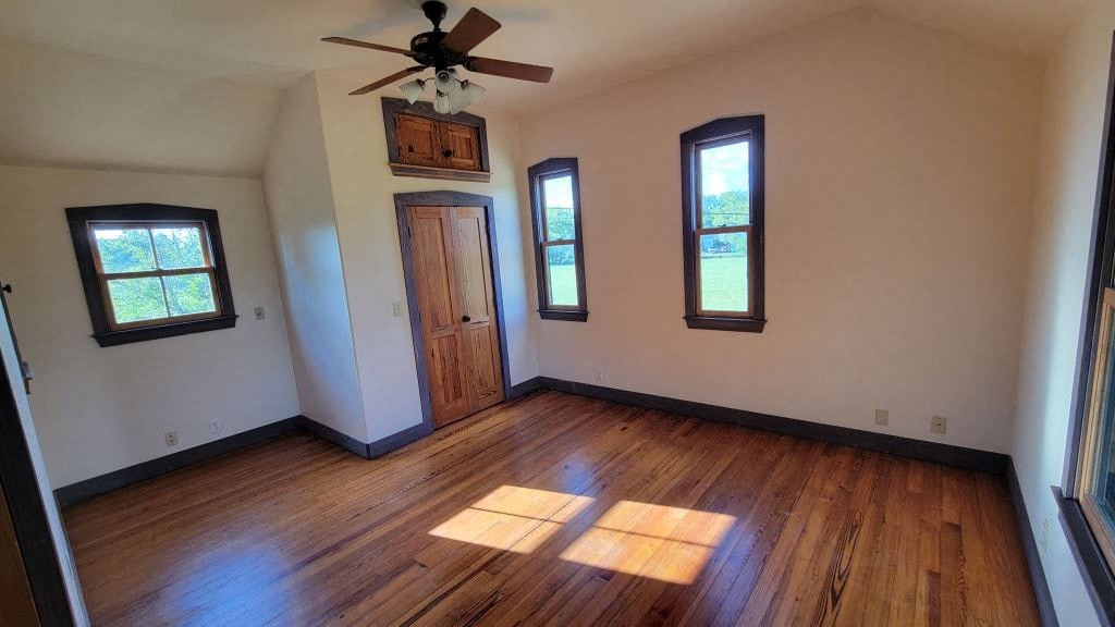 a empty living room with wooden floors and a ceiling fan