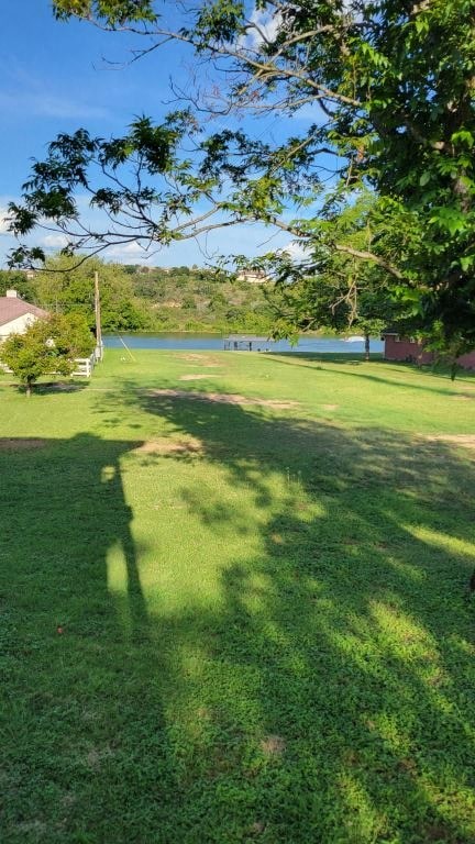 a grassy field with a lake in the background