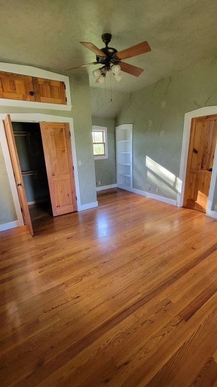 an empty living room with wood floors and a ceiling fan
