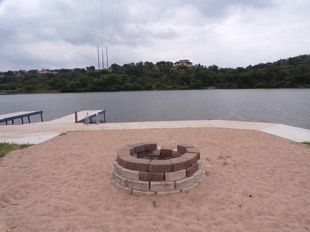 a fire pit on the beach near a lake