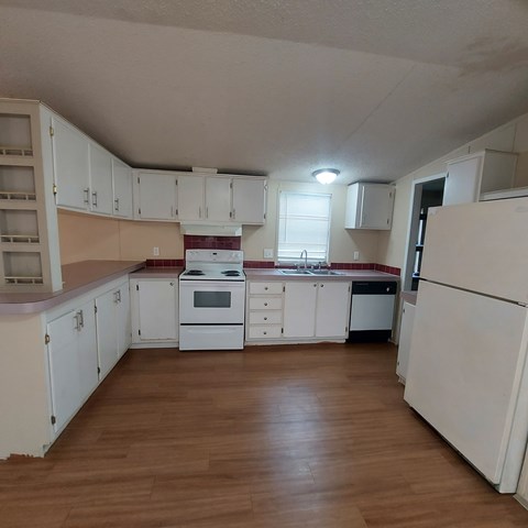 A kitchen with white cabinets and a wooden floor.