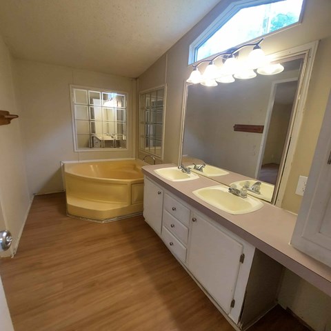 A bathroom with a yellow bathtub and white cabinets.
