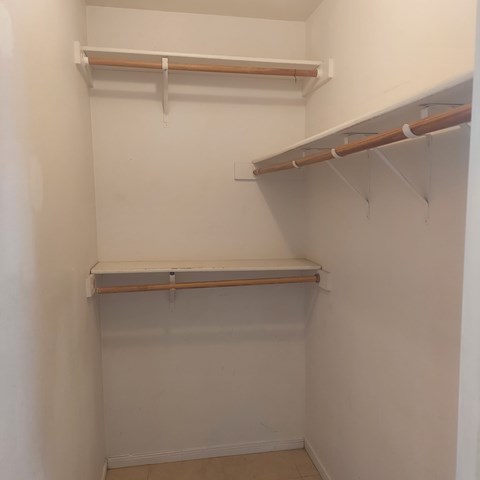 Empty white closet with shelves and hooks.
