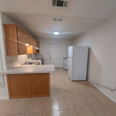 A kitchen with a white counter top and wooden cabinets.