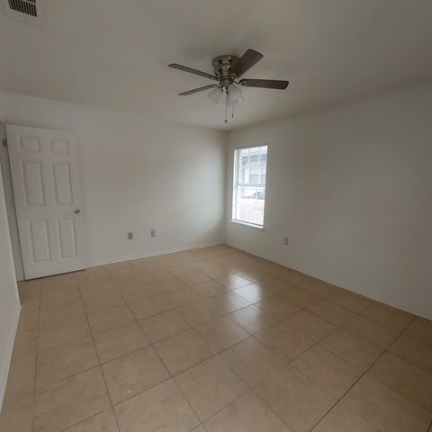 A room with a ceiling fan and tile flooring.