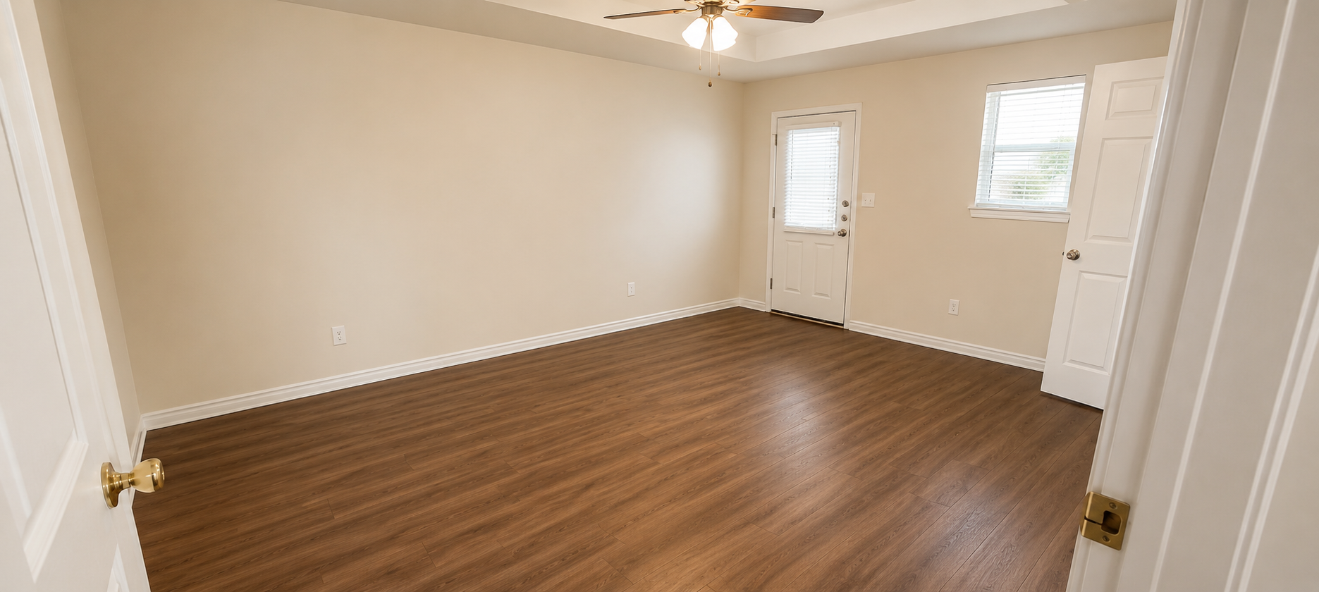 A room with wooden flooring and white walls.