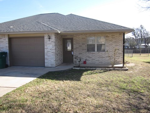 A house with a brown garage door and a brick wall.