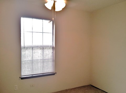 A room with a window covered in blinds and a light hanging from the ceiling.